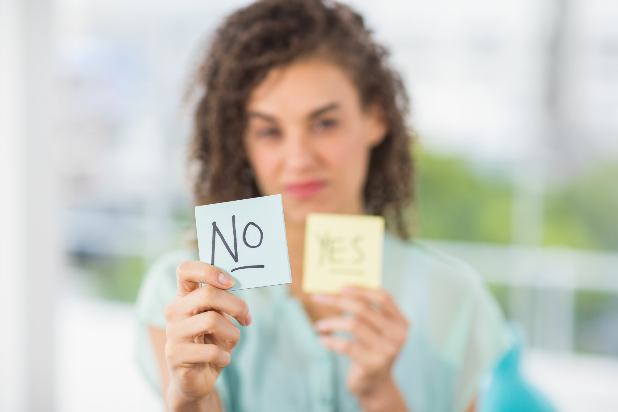 Profissional segurando dois bilhetes, um com "No" e outro com "Yes", representando a decisão entre recusar e assumir uma entrega